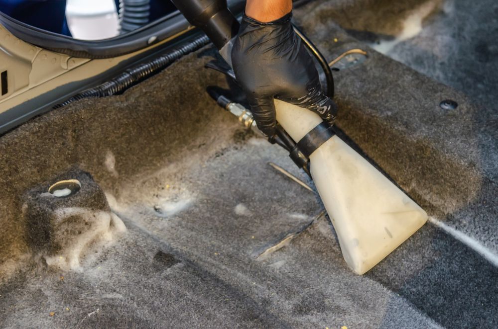 Hot-water extractor deep-cleaning a car's carpet